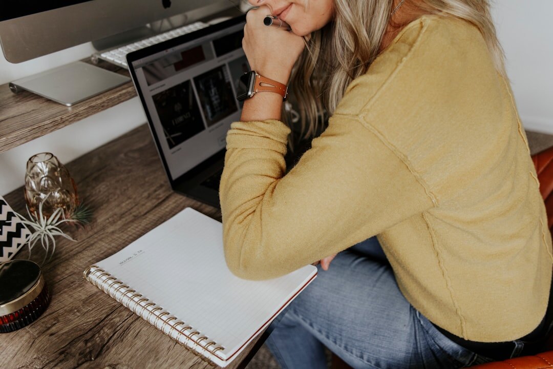 Editor reviewing an article draft on a laptop with a notebook nearby